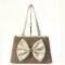 Neutral-toned structured handbag with double handles and a large ivory bow detail on the front, displayed on a minimalist background.